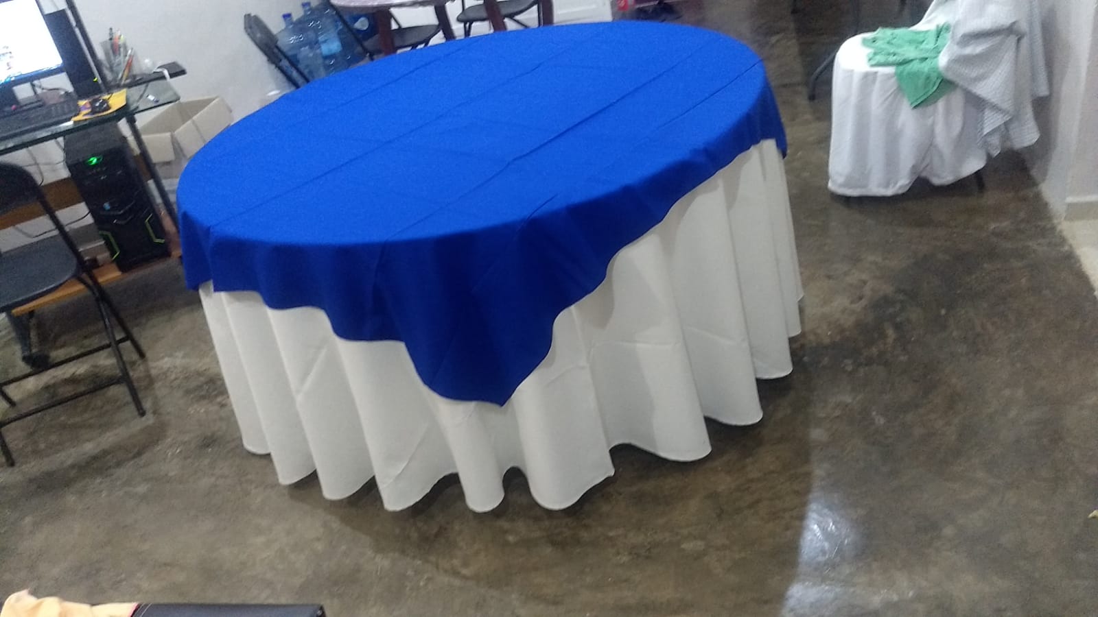 Mesa redonda con mantel blanco y cubremantel azul rey